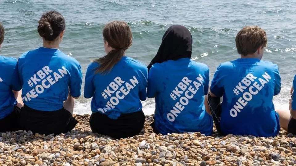Group wearing #KBROneOcean shirts at the beach